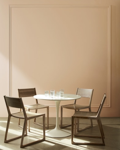 A Hidden Oaks-painted dining room with white cuckoo clock, wood chairs, and modern white table with a house plant.