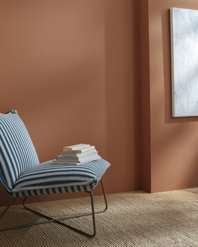 A Georgia On My Mind-painted wall behind a striped armless lounge chair with books on it.