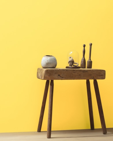 Ceramic artifacts are placed on a modern wooden table in front of a wall painted Yellow Highlighter.